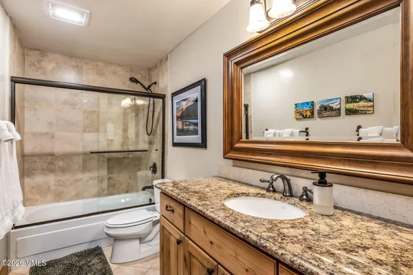 a bathroom with a granite countertop sink toilet and shower