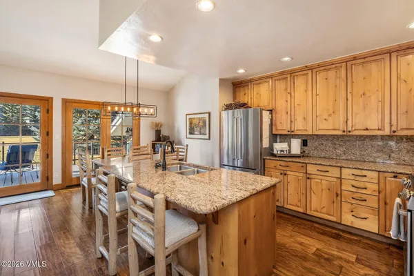 a kitchen with stainless steel appliances granite countertop a table chairs refrigerator and wooden cabinets