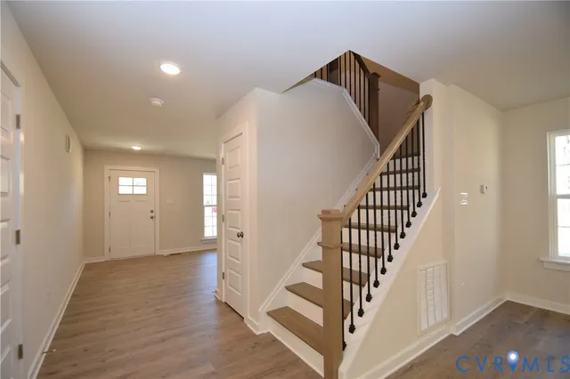 a view of a hallway with entryway and wooden floor