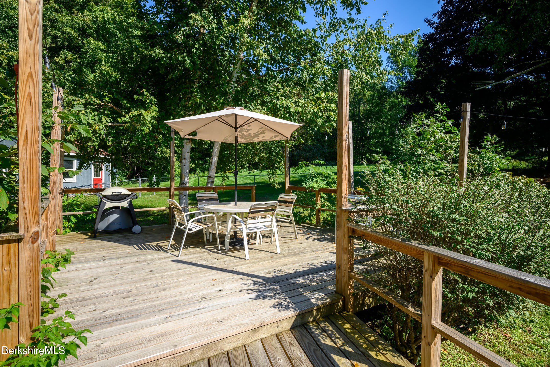 69 County Road Pownal, VT 05261 - Photo 11 of 33 a view of a patio with a dining table and chairs under an umbrella with a small yard