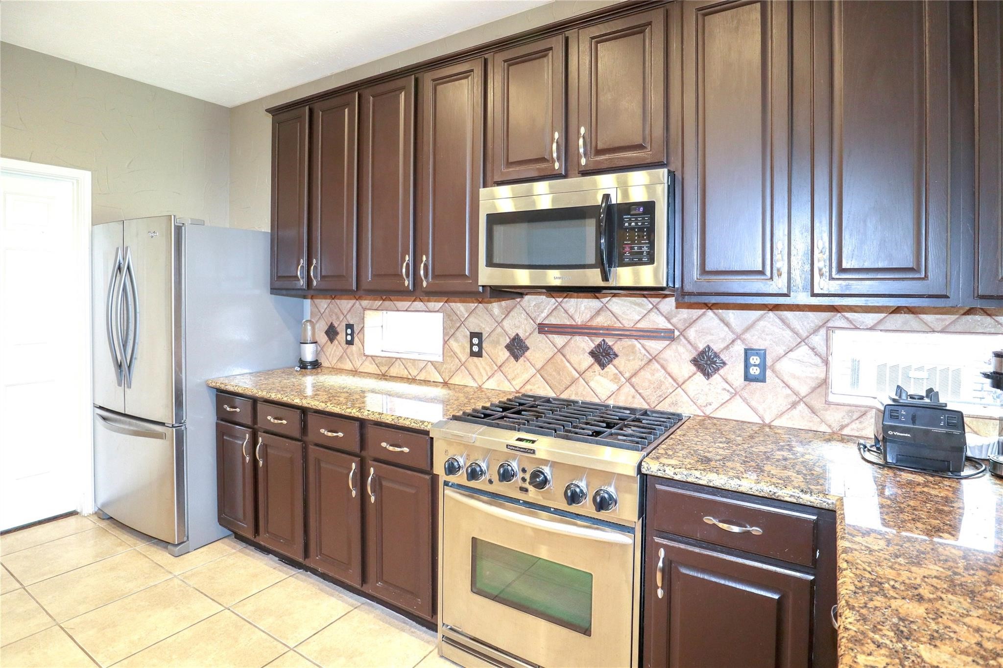 23207 Olive Ridge Court Katy, TX 77494 - Photo 23 of 45 a kitchen with granite countertop wooden cabinets and stainless steel appliances