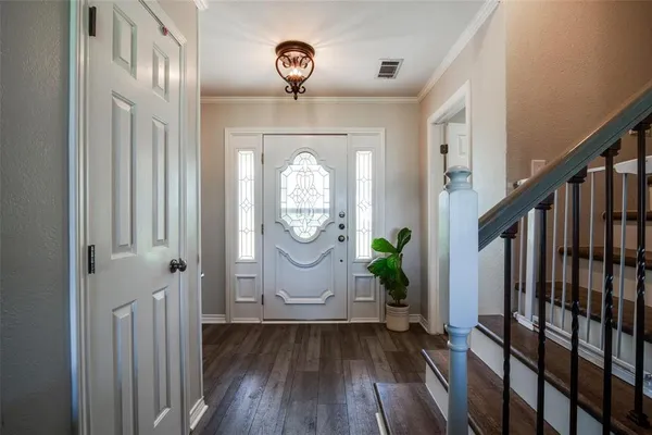 a view of a hallway to a livingroom with wooden floor and stairs