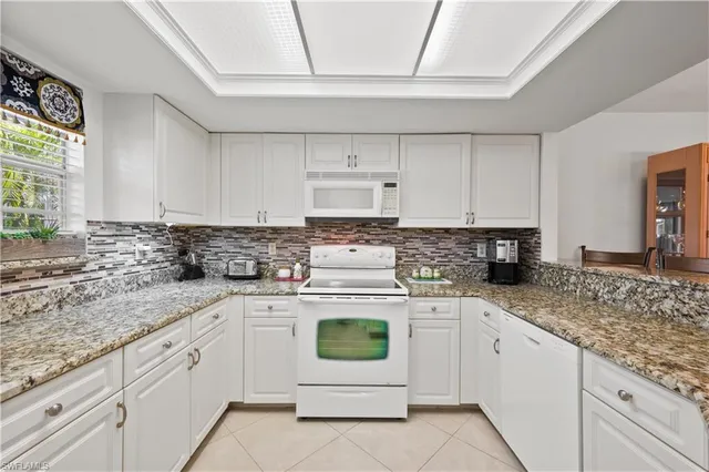 a kitchen with granite countertop white cabinets and a sink