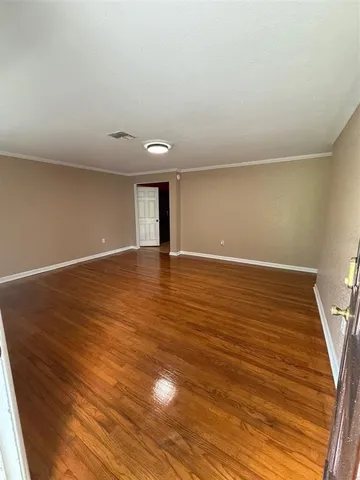 a view of an empty room with wooden floor