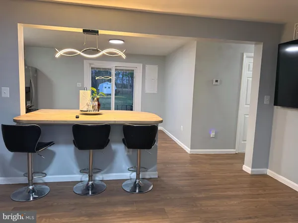 a dining room with wooden floor a chandelier a wooden table and chairs