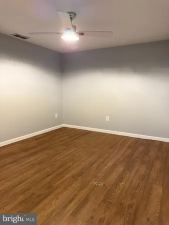 an empty room with wooden floor and fan