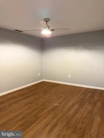 an empty room with wooden floor and fan
