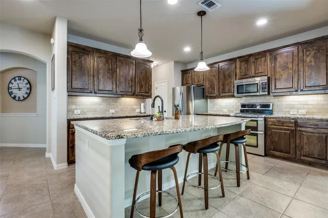 a kitchen with kitchen island granite countertop wooden cabinets a stove a oven a counter and a refrigerator