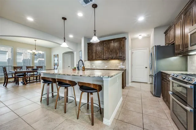 a kitchen with kitchen island stainless steel appliances a stove center island a table and chairs