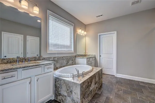 a bathroom with a granite countertop bathtub sink vanity and mirror