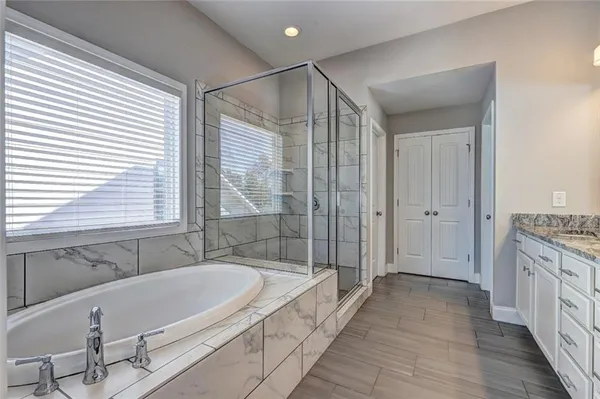 a bathroom with a granite countertop tub sink and mirror