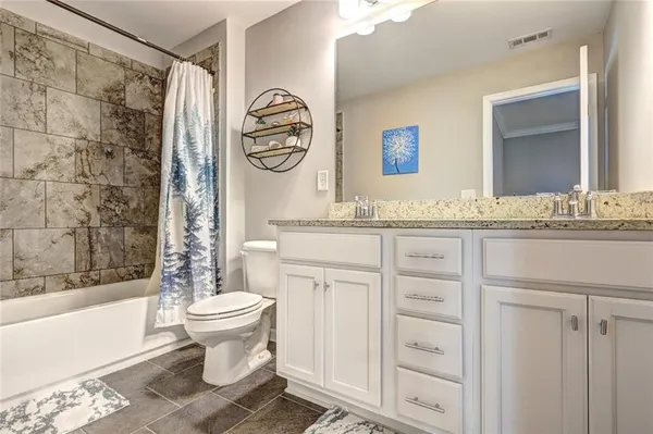 a bathroom with a granite countertop sink toilet mirror vanity and bathtub