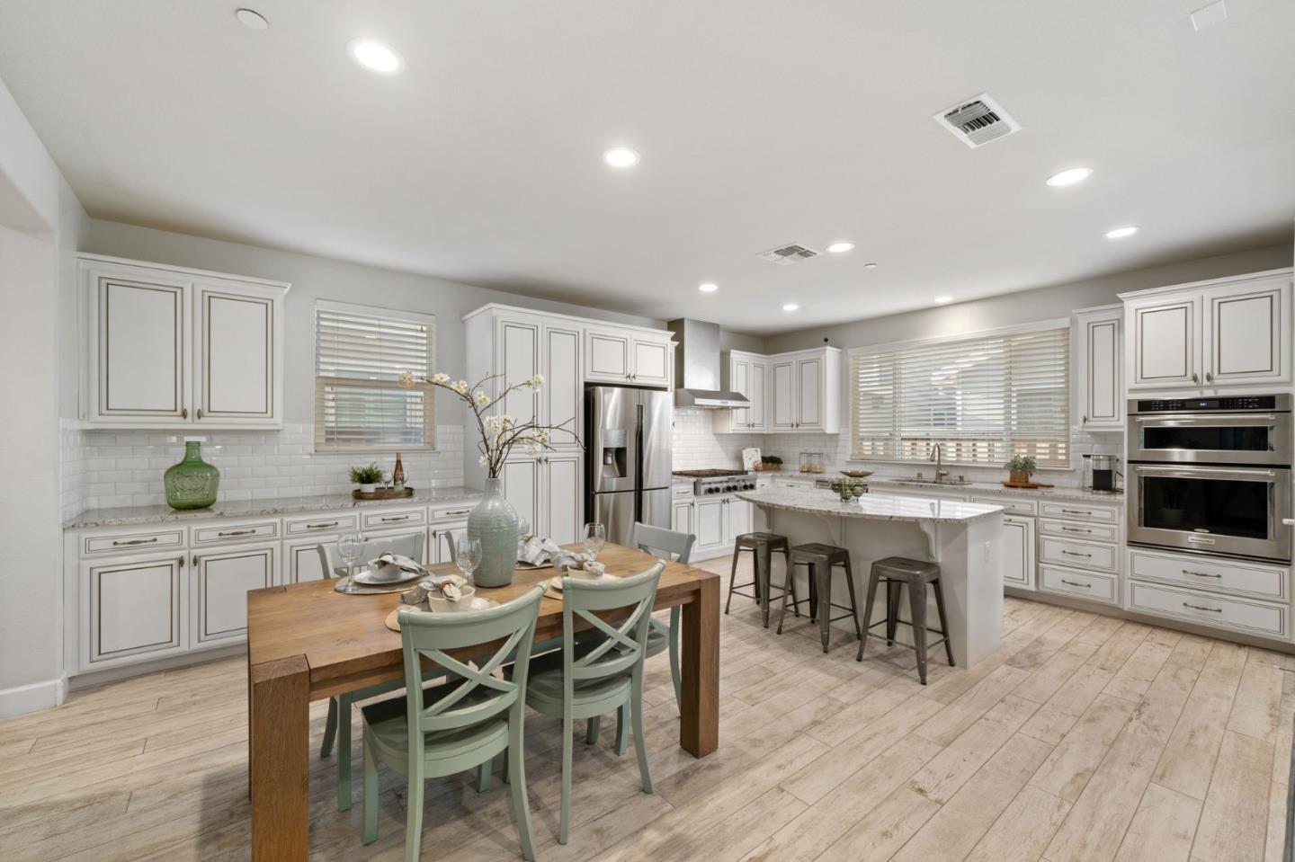 11958 Glaskin Place Dublin, CA 94568 - Photo 11 of 41 a large kitchen with kitchen island a dining table chairs and white cabinets