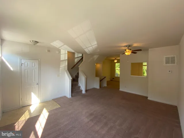 an empty room with windows and ceiling fan