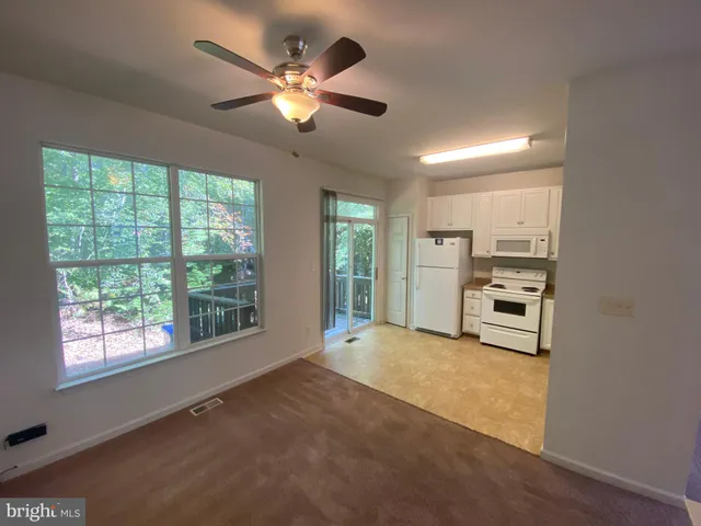 a view of an empty room with a chandelier fan