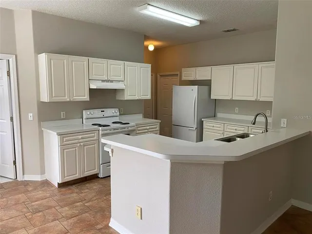 a kitchen with a sink a stove a refrigerator and cabinets