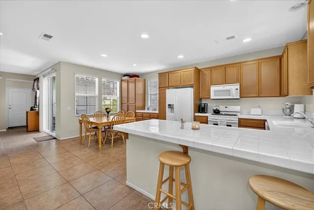 a kitchen with stainless steel appliances granite countertop a stove a sink a dining table and chairs