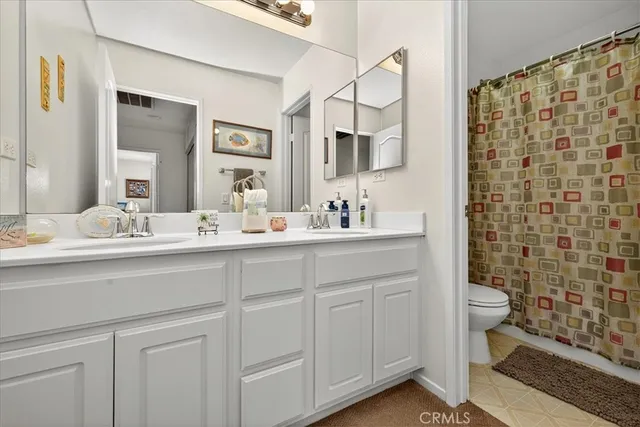 a bathroom with a double vanity sink toilet and shower