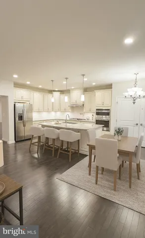 a dining hall with stainless steel appliances a dining table chairs and view of kitchen