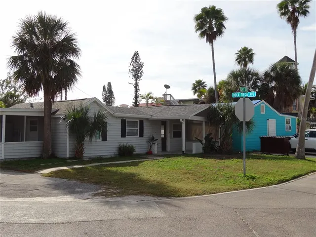 a view of a house with a yard and palm trees