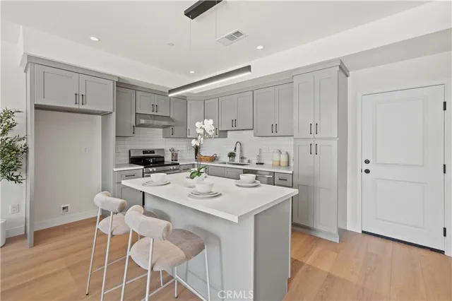 a kitchen with a sink a stove a refrigerator and white cabinets