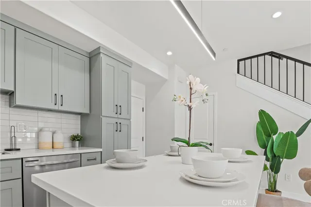 a kitchen with stainless steel appliances a white table a potted plant and a window