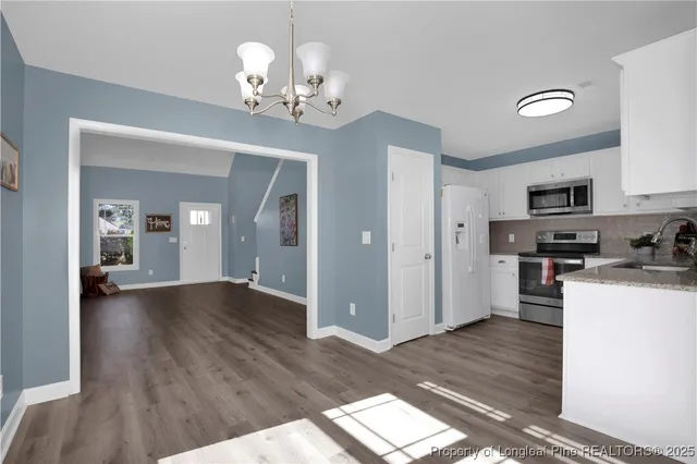 a view of a kitchen with a sink wooden cabinets and refrigerator
