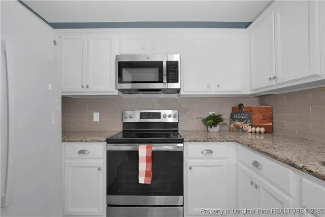 a kitchen with white cabinets and black appliances