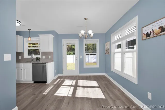 a view of an empty room with a window and kitchen view