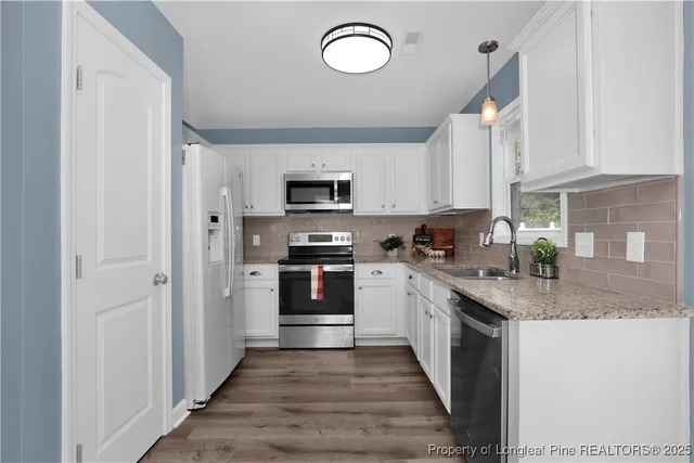 a kitchen with granite countertop a stove top oven a sink dishwasher and a refrigerator with wooden floor
