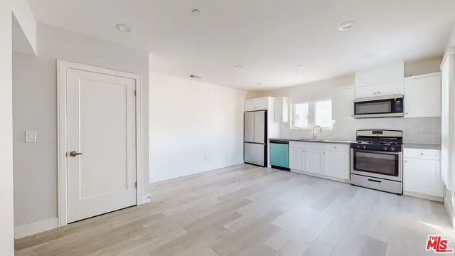 a view of a kitchen with a sink stove cabinets and empty room