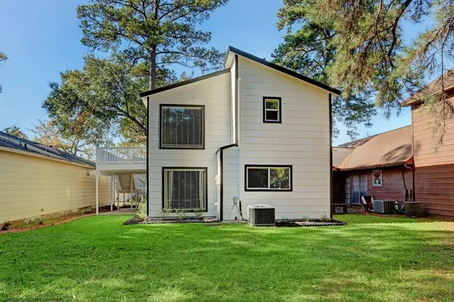 a view of a yard in front of a house with plants and large tree