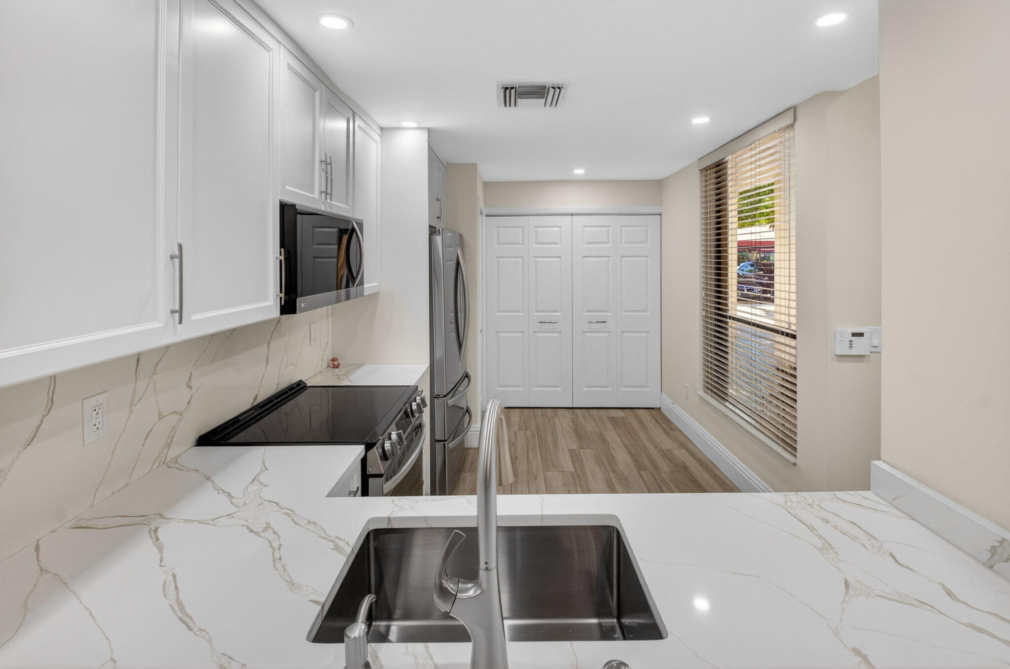 7484 La Paz Boulevard, Unit 103 Boca Raton, FL 33433 - Photo 17 of 50 a kitchen that has a sink and a stove top oven