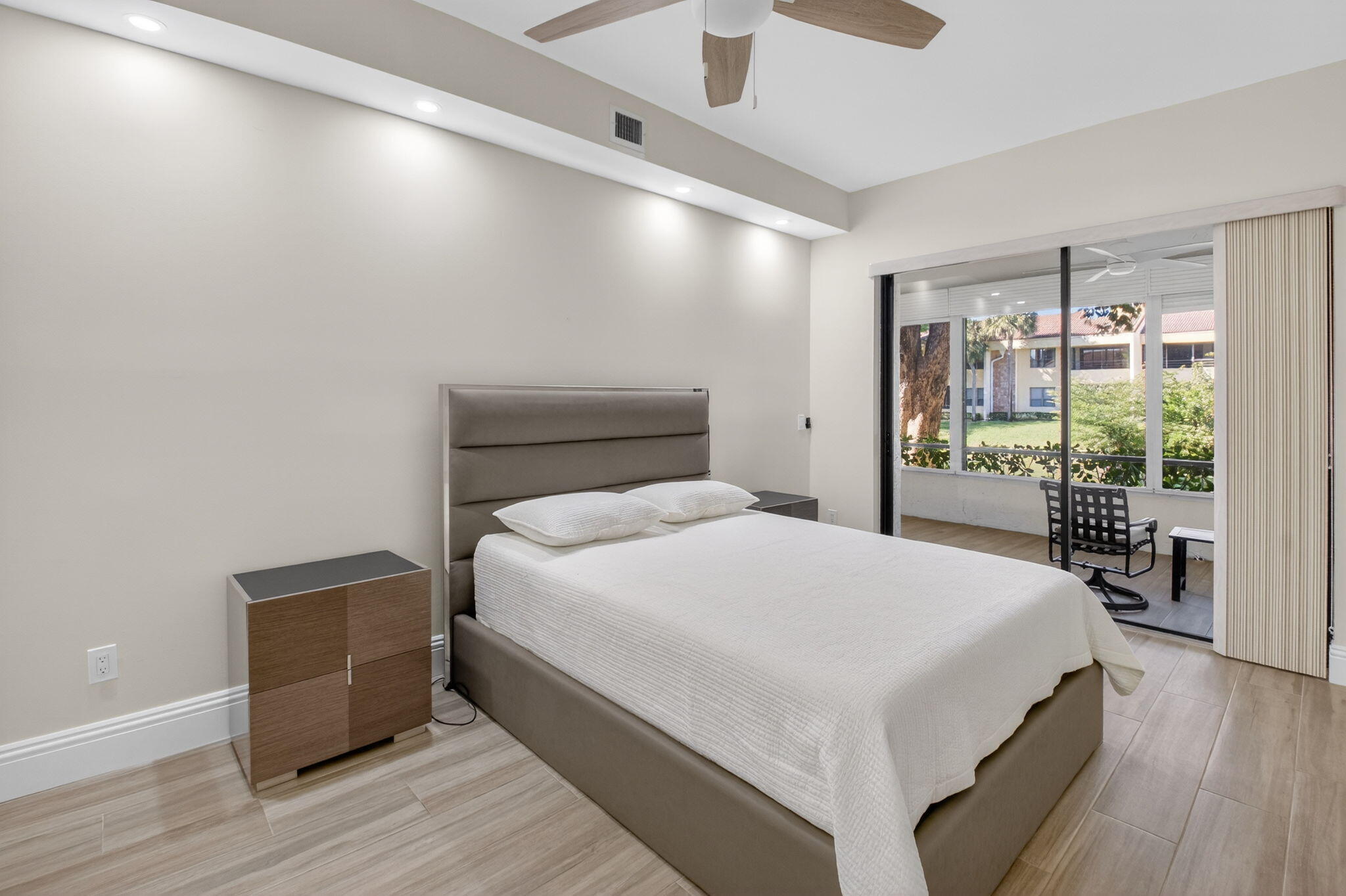 7484 La Paz Boulevard, Unit 103 Boca Raton, FL 33433 - Photo 24 of 50 a bedroom with a large bed and wooden floor