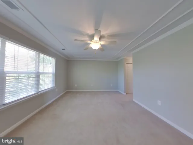 an empty room with chandelier fan and windows
