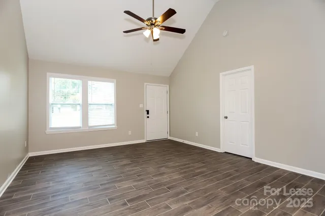an empty room with wooden floor fan and windows