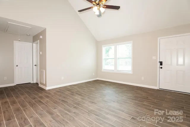 a view of an empty room with wooden floor and a window