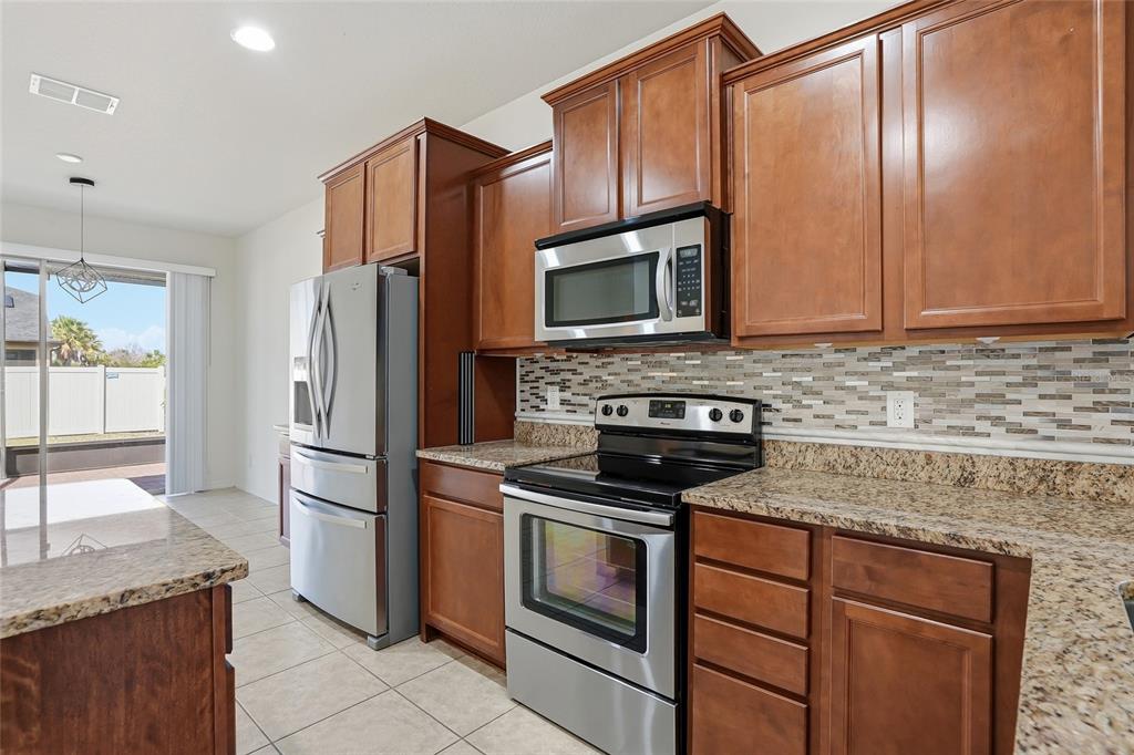 1724 Passage Key Lane Ruskin, FL 33570 - Photo 13 of 46 a kitchen with granite countertop wooden cabinets and stainless steel appliances