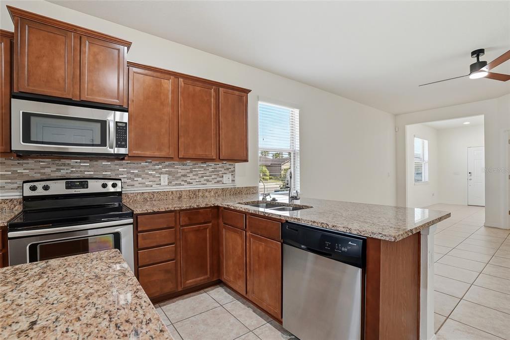 1724 Passage Key Lane Ruskin, FL 33570 - Photo 14 of 46 a kitchen with stainless steel appliances granite countertop a stove microwave and sink