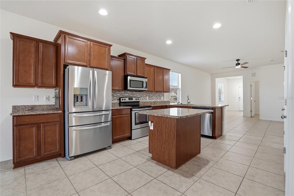 1724 Passage Key Lane Ruskin, FL 33570 - Photo 15 of 46 a kitchen with stainless steel appliances granite countertop a refrigerator and a stove top oven
