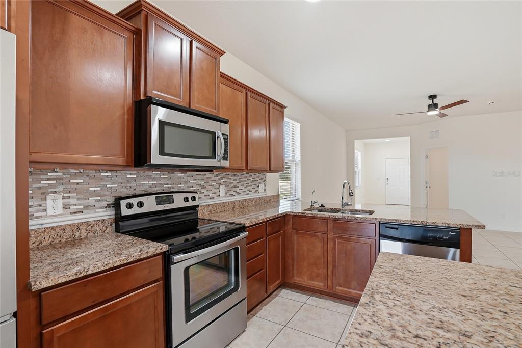1724 Passage Key Lane Ruskin, FL 33570 - Photo 17 of 46 a kitchen with stainless steel appliances granite countertop wooden cabinets a stove top oven and granite counter tops