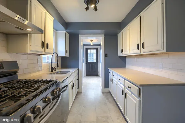 a kitchen with granite countertop a sink stove and cabinets