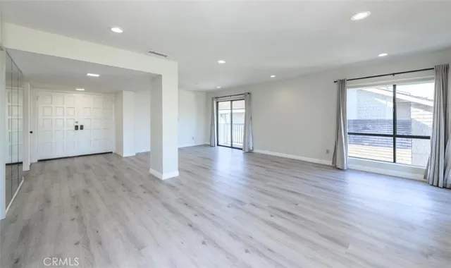 a view of an empty room with wooden floor and glass door