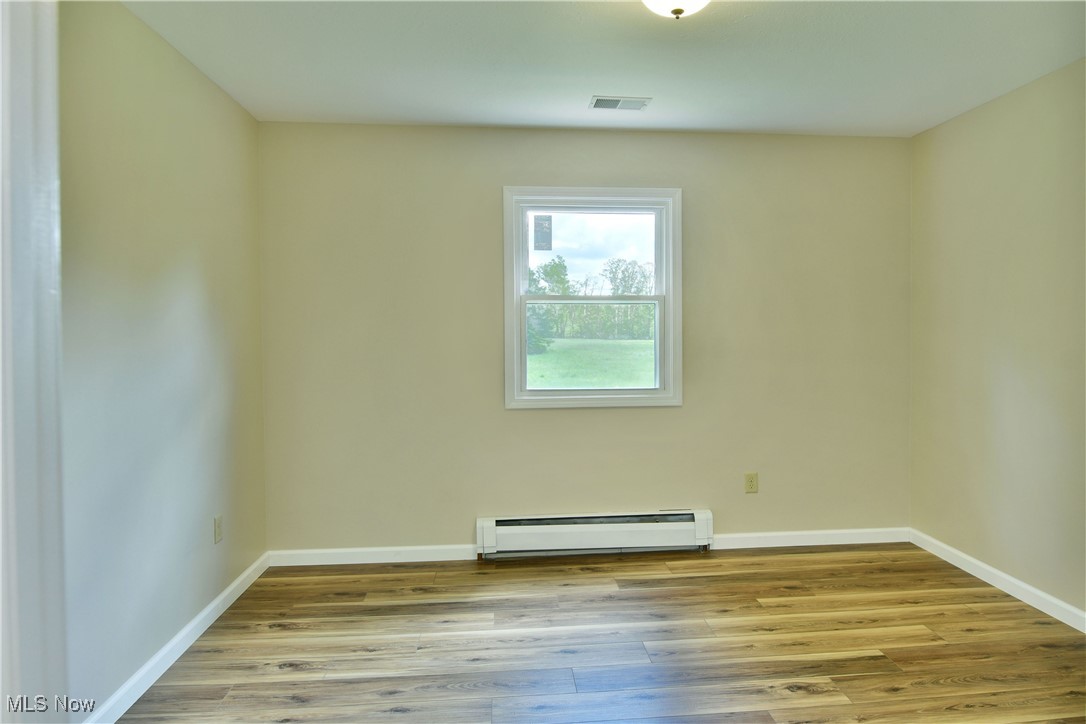 2153 Stillwagon Road Southeast Warren, OH 44484 - Photo 27 of 50 Empty room with a baseboard radiator, wood finished floors, and baseboards