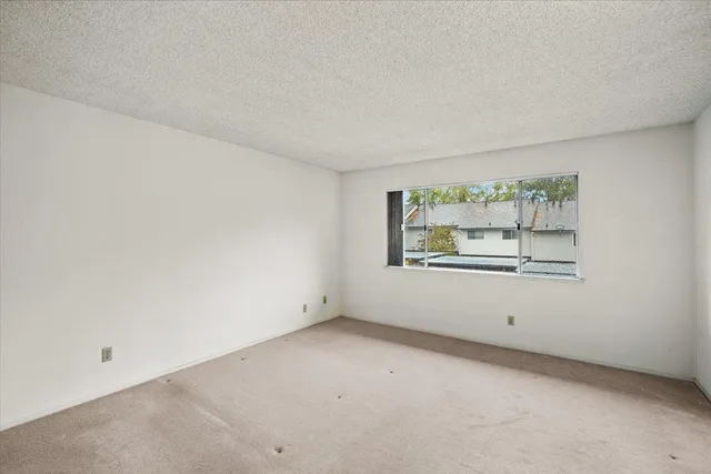 a view of an empty room with a window and a kitchen