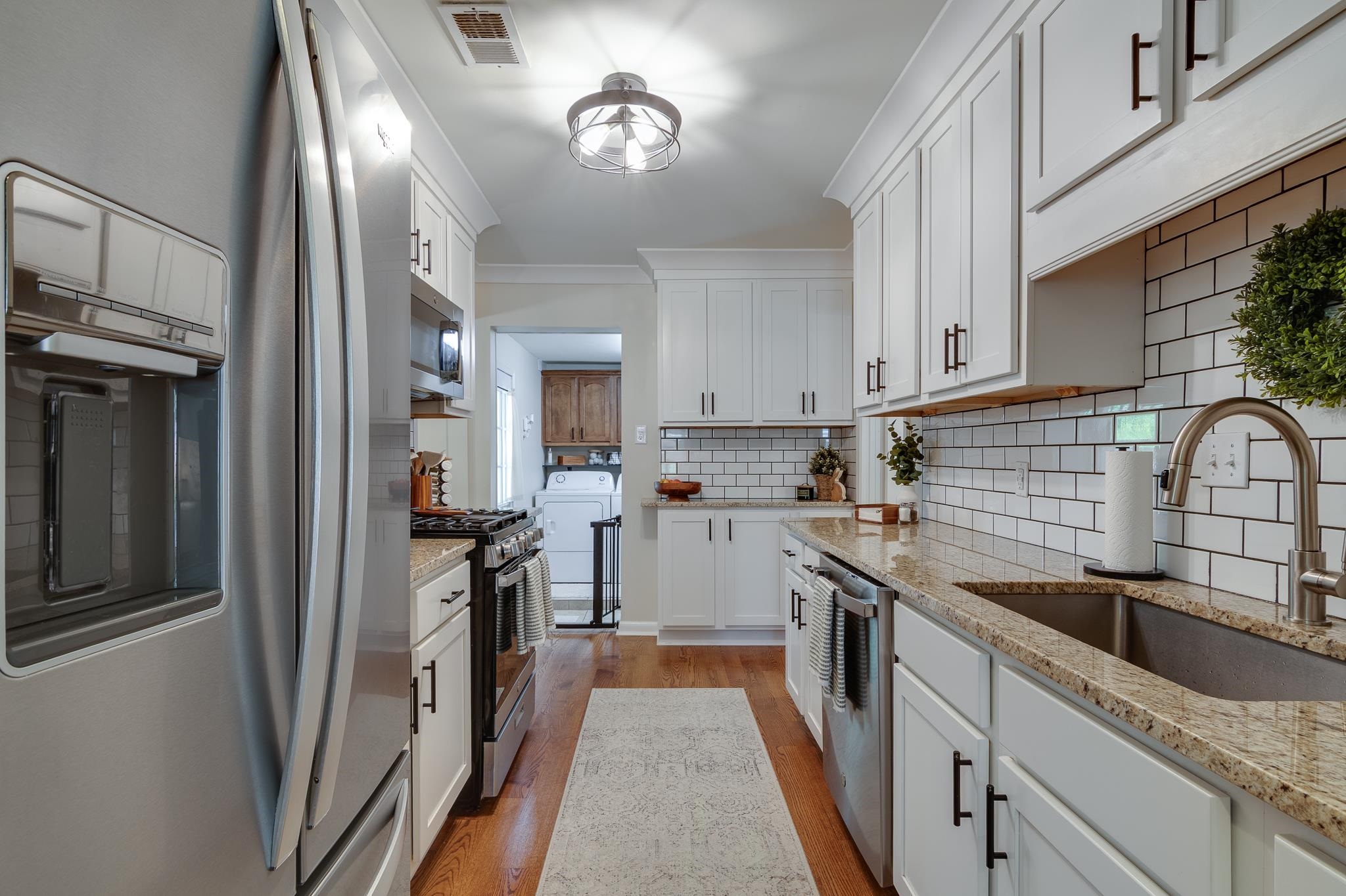 4961 Sea Isle Road Memphis, TN 38117 - Photo 9 of 29 Kitchen with light wood-type flooring, visible vents, appliances with stainless steel finishes, a sink, and backsplash