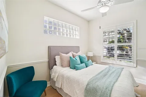 a view of a white house with a large tree and wooden fence