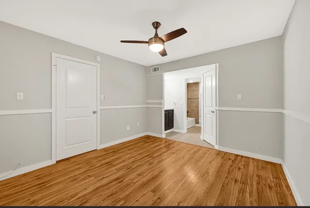 a view of empty room with wooden floor and fan
