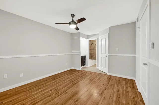 a view of empty room with wooden floor and ceiling fan