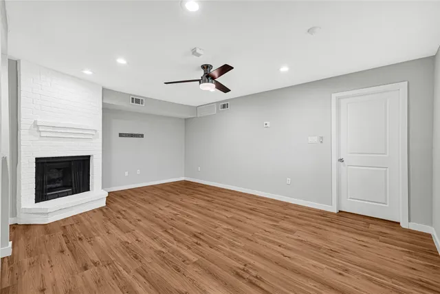 a view of an empty room with wooden floor fireplace and a window